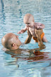 Father holding baby up high in swimming pool
