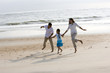 Photo: Hispanic family holding hands skipping on beach Hispanic family holding hands skipping on beach