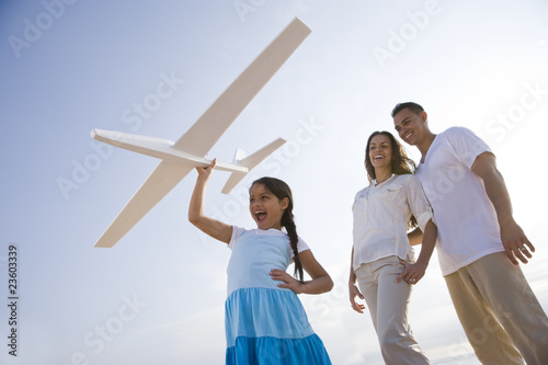 Photo: Hispanic family and girl having fun with toy plane Hispanic family and girl having fun with toy plane
