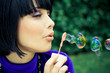 Young beautiful woman blowing soap bubbles