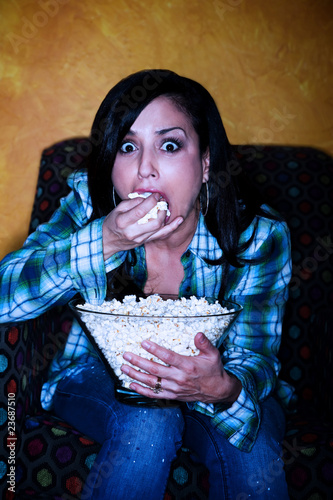 Photo: Pretty Hispanic woman with popcorn watching television Pretty Hispanic woman with popcorn watching television