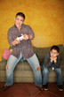 Man Playing Video Game with Bored Young Boy