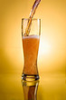 Glass of beer close-up with froth over yellow background
