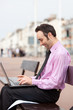 Smart young businessman sitting outside with laptop