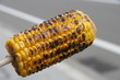 Grilled slightly burnt Corn on a cob on a stick