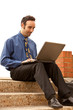 Man sitting outside on steps looking at his laptop