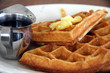 Waffles with butter and sweet syrup in a jug