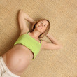 Pregnant woman relaxing and stretching on bamboo background