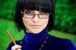 young thinking woman in glasses with pen