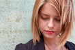 Thoughtful Attractive blonde girl by concrete wall
