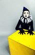 Сircus fashion mime posing near a yellow square on a grey backgr