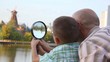 father and son stands and looks through magnifying glass