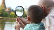 father and son standing and looks through magnifying glass