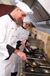 two chefs cooking on stove in kitchen