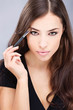 black hair woman applying make up with brush in her right hand black hair woman applying make up with brush in her right hand