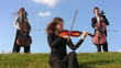 three musicians sits on hill and plays violins three musicians sits on hill and plays violins