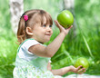 Little girl portrait with two green apples in her hands outdoor
