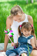 Smiling mother and daughter in jeans with colorful toy outdoor