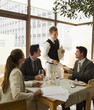 Waiter handing business people menus at restaurant table