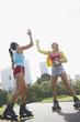 Women on rollerblades high fiving