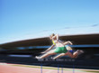 Runners jumping over hurdles