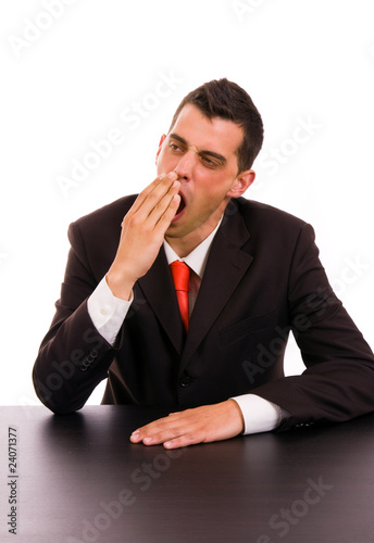 Photo: yawning young business man on the desk, on white background yawning young business man on the desk, on white background