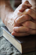 Praying hands on a Holy Bible
