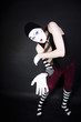 Funny mime in white gloves on black background