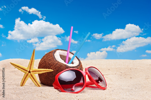 Foto: A coconut, starfish and a sunglasses on a beach A coconut, starfish and a sunglasses on a beach
