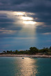 Rays of sun breaking through the clouds over boat on water