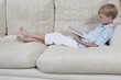 Boys sits on sofa reading a digital book