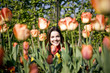 A young woman sitting amongst tulips, smiling