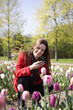 A young woman photographing flowers with her phone
