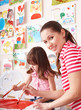 Child painting with teacher in preschool.