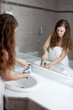 dressed in towel beautiful woman washing hand at modern bathroom