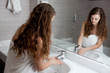 dressed in towel beautiful woman washing hand at modern bathroom