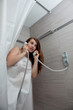 gorgeous woman behind curtain making a call at modern bathroom
