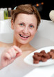 Happy woman eating chocolate while having a bath Happy woman eating chocolate while having a bath