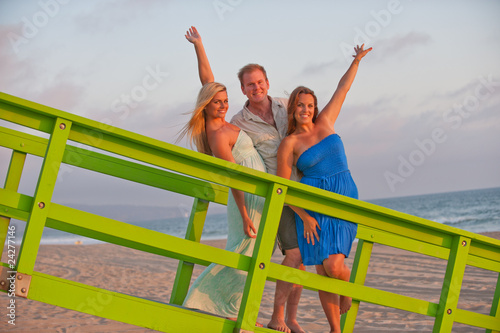 Photo: two beautiful women and man on California beach coast two beautiful women and man on California beach coast