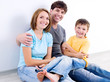 Happy family in casuals sitting on the floor