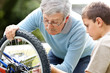 Senior man and a ittle boy repairing a bicycle in a park