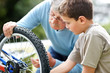 Little boy and his grand father rapairing a cycle