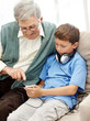 Senior man sitting with his grandson holding a mp3 player
