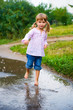 Girl junps barefoot in a puddle