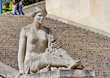 Femme souriante assise devant un escalier de pierre.