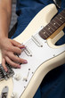 Young woman playing white electric guitar
