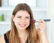 Portrait of a delighted woman using a powder brush