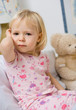 little girl in bed touching ear