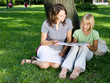 Mother and Daughter reading the Book in a park.Education concept