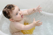 Cute baby playing with water in white tub
